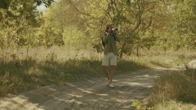 Photographer Taking Pictures With DSLR Camera On Forest Road. Traveler Tourist Shooting Nature