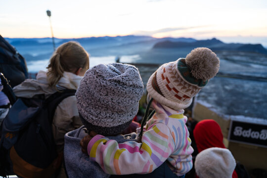 View of people wearing winter hats watching the sunrise over the misty mountain landscape from Adam's Peak Ratnapura, Sabaragamuwa Province, Sri Lanka.