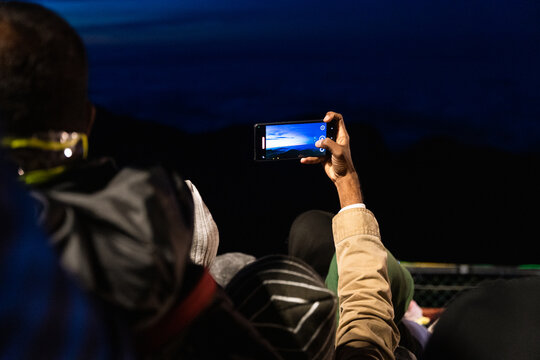 View of a person taking a photo with a smartphone of the sunrise from Adam's Peak surrounded by a crowd of pilgrims in Ratnapura, Sabaragamuwa Province, Sri Lanka.