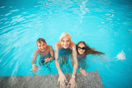 Smiling teen, boy and girl swimming in pool. Happy children playing in water during summer vacation. Kids enjoying outdoor recreation, leisure time and active lifestyle in sunny weather.