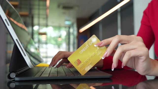 Woman holding credit cards while making a successful online payment on laptop computer, representing e-commerce, digital banking, and secure online shopping at home.