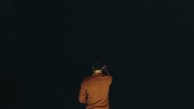 Back view of a Hindu man scattering yellow flower petals into the Ganges during the nightly Ganga Aarti at Varanasi, a sacred ritual of devotion on the river ghat