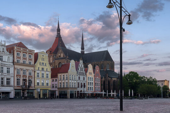 St Mary's Church rises behind gabled houses on Neuer Markt at evening in Rostock, Mecklenburg-Western Pomerania, Germany.