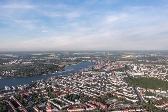 An aerial panorama shows Rostock, the Warnow River, rooftops and distant wind turbines in Mecklenburg-Western Pomerania, Germany.