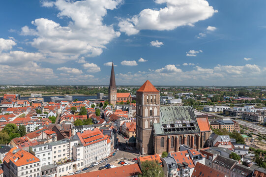 Historic church towers rise above red roofs in Rostock old town, seen from an aerial view in Mecklenburg-Western Pomerania, Germany.