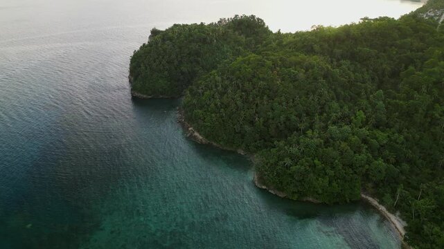 Aerial overhead shot of Virac, Catanduanes with lush tropical forest, rocky coastline, and clear coastal water along the shoreline