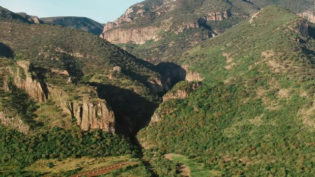 Backward aerial over canyon cliffs, green mountains, and valley fields in Sierra P&eacute;njamo, Guanajuato