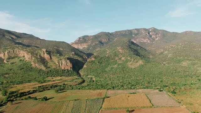 Aerial dolly in over canyon cliffs, mountains, forest, and agricultural fields in Guanajuato, Garita Canyon, Sierra Penjamo