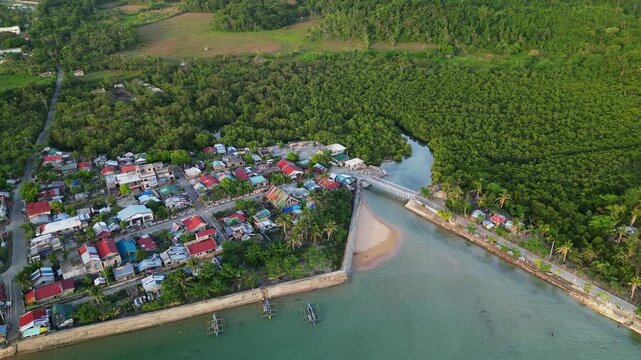 Panoramic aerial forward shot of Magnesia Del Norte in Virac, Catanduanes, with a coastal barangay village, and lush tropical greenery