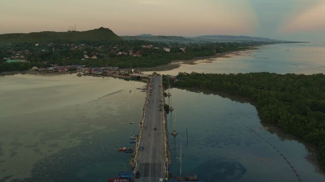 Drone overview approaching coastal bridge at sunset in Bohol