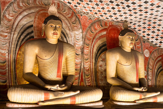 View of ancient seated Buddha statues with intricate murals in the Dambulla Cave Temple Dambulla, Central Province, Sri Lanka.