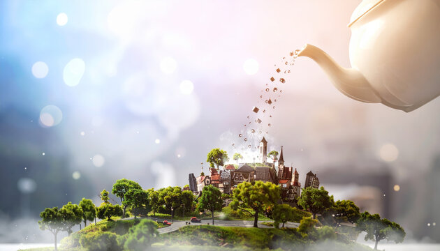 A Teapot Pours a Miniature City with Green Trees and Buildings into a Dreamy Landscape