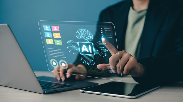 A person's finger interacts with a transparent screen displaying an AI brain icon and various data points, alongside a laptop and tablet.
