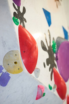 Vertical shot of indoor climbing wall showing colorful holds and route markers, supporting fitness training and recreation concepts