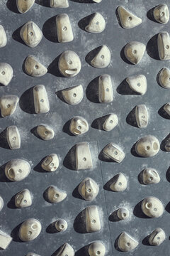 Vertical shot of indoor climbing wall featuring mounted holds and chalk marks, supporting fitness training and recreation concept