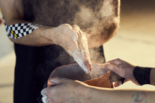 Close up of athletes clapping chalked hands over climbing bag, preparing for bouldering session and grip control