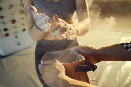 Close up of young adult athlete chalking hands before indoor climbing, preparing for grip and performance. Useful for fitness training, sports motivation, active lifestyle marketing