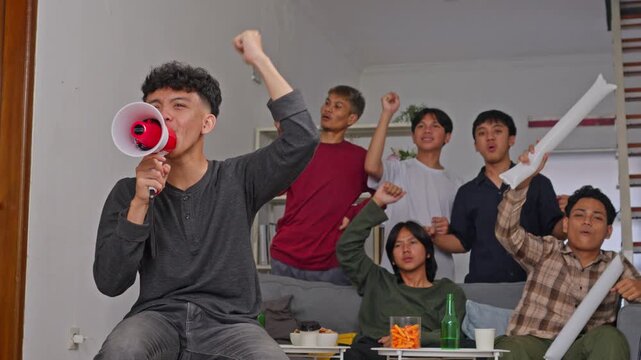 Group of ecstatic young men cheering with megaphone while watching sports match together