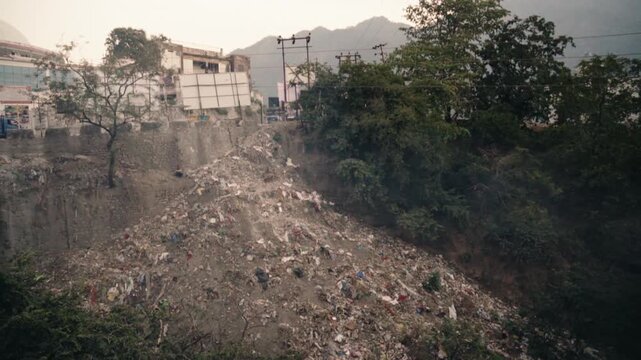 Vast landfill with tons of plastic waste and trash illegally dumped on a hillside, creating an environmental disaster and showcasing the serious problem of pollution in developing countries
