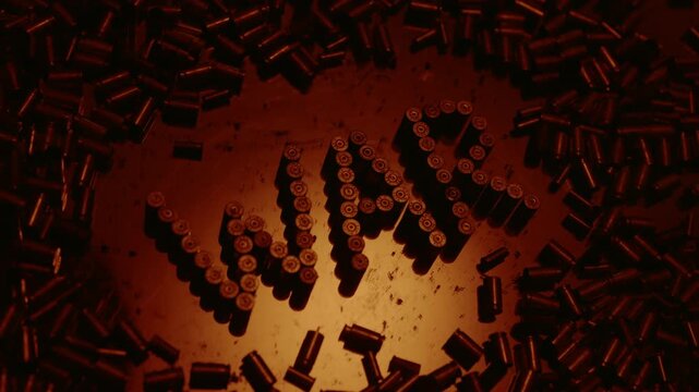 The word war, written with 9mm bullet casings, dissolving on a dark, gritty surface under dramatic lighting, symbolizing the end of conflict, a call for peace, or the chaos of battle