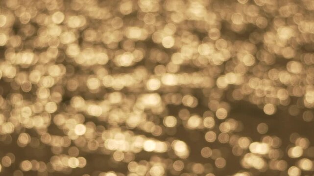 Bokeh glitter reflection of shimmering golden light on the water surface creating a peaceful abstract background for artistic projects