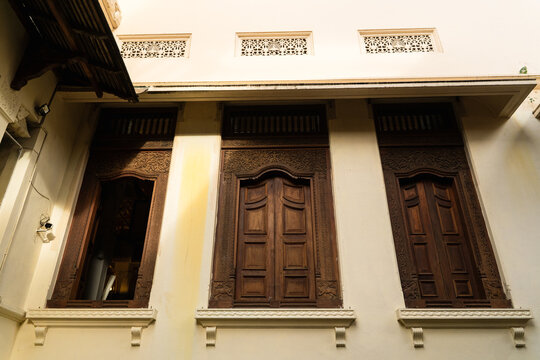 View of intricately carved wooden windows with traditional motifs on a historic building facade Kandy, Central Province, Sri Lanka.
