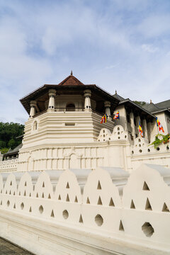 View of the Temple of the Sacred Tooth Relic with its iconic octagonal tower and decorative white walls under a bright sky in Kandy, Central Province, Sri Lanka.