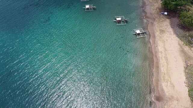 Aerial 4K drone view of traditional banca boats on turquoise tropical bay in Puerto Princesa, Philippines