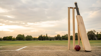 Cricket Bat Ball and Stumps on Outdoor Pitch at Sunset