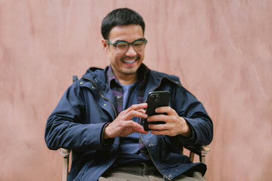 adult asian man using mobile, cell phone.young male person.posing smiling laughing look excited surprised thinking positive happy.empty,copy space for text advertising.background