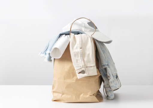 Pile of casual denim clothes prepared for donation, recycling or secondhand resale in sustainable fashion culture. Denim garment in paper back against white background