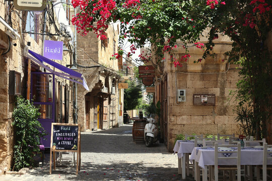BATROUN, LEBANON  May 18, 2024: Charming cobblestone street in the historic old town of Batroun featuring traditional stone buildings, outdoor seating, and vibrant bougainvillea.