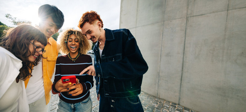 Gen Z friends laughing while looking at phone