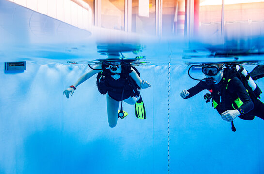 Underwater view of a scuba diving instructor guiding a student during a training lesson in a swimming pool