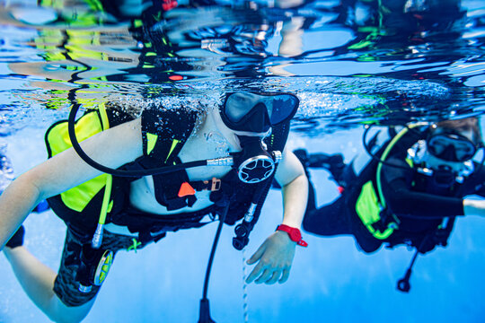 Close-up underwater view of a student and instructor scuba diving in a swimming pool during a training lesson