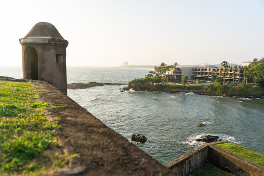 View of a historic stone watchtower on the ramparts of Galle Fort overlooking the ocean and a coastal resort in Galle, Southern Province, Sri Lanka.