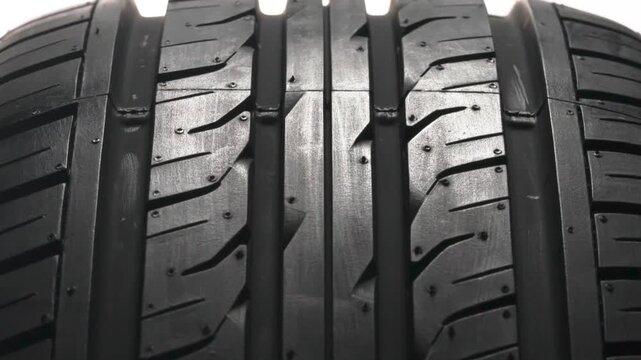 Rotation of a New Tire. New car wheel close-up slowly spinning showing tread pattern on white background