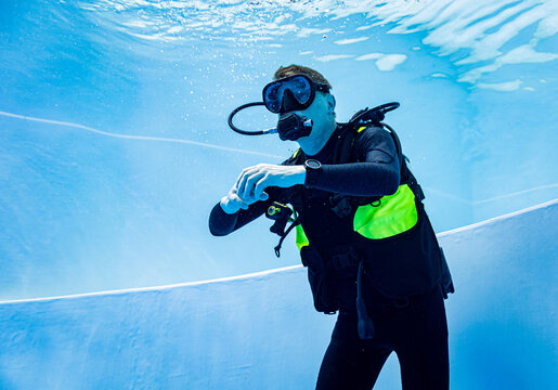 Scuba diver descending in a deep blue swimming pool