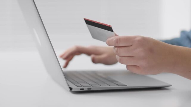 Close up of hands using a laptop and holding a credit card, illustrating online shopping or internet banking. Modern technology and secure payment methods for digital transactions