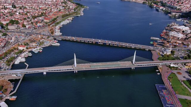 4K aerial view of Istanbul's cable-stayed Hali&ccedil; Metro Bridge and Atat&uuml;rk Bridge crossing the Golden Horn between Beyoğlu and the historic peninsula with ferries and boats.