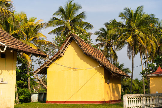 View of a traditional yellow building with a tiled roof surrounded by lush palm trees under a clear sky in Galle, Southern Province, Sri Lanka.