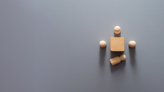 Minimalist wooden peg figures arranged around a central wooden block with one figure lying apart from the group, symbolising employee turnover, workforce reduction, staff resignation, talent loss.