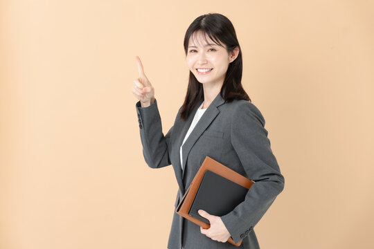 ファイルを持って指差しをする笑顔のビジネスウーマン