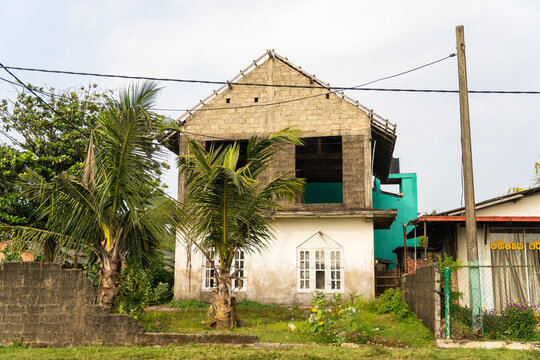 View of a two-story building under construction with unfinished concrete blocks and palm trees in Galle, Southern Province, Sri Lanka.