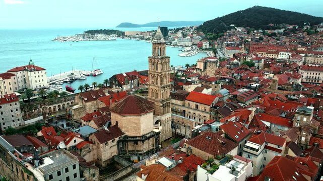 Cinematic aerial drone footage of Split featuring the Adriatic coastline, historic old town, marina, and Mediterranean atmosphere. Ancient architecture mixed with modern coastal life