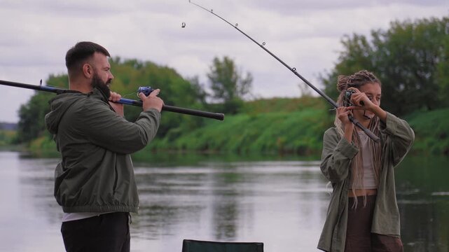 Romantic couple enjoying quiet fishing together by throwing lines into a calm river, spending time in nature, and doing their common hobby on a calm day
