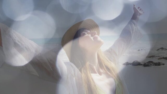 Woman posing arms wide on shoreline, bokeh overlay receding and revealing beachwear for travel