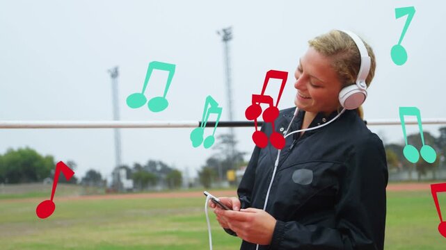Girl tapping phone on sports field with headphones, nodding to music while animated notes floating
