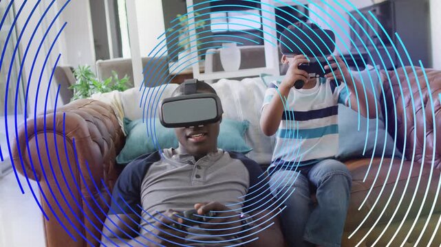 Father and son sitting on couch, child lifting headset, starting VR gaming as blue rings overlay