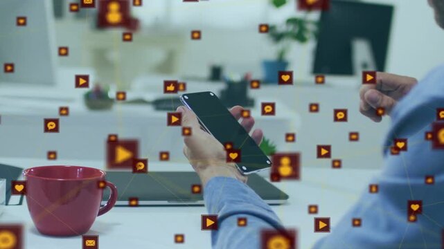 Man holding phone at desk and tapping screen, sending social icons floating for marketing reach
